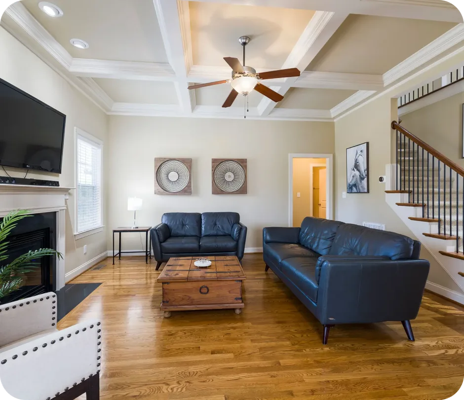 Finished basement living room with leather seating, hardwood flooring and staircase
