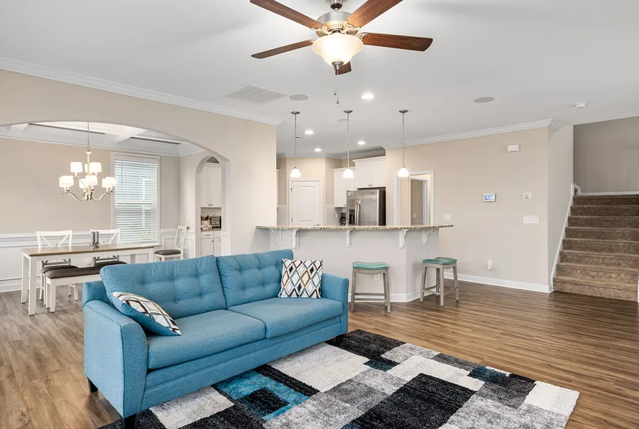 Finished basement living area with blue sofa, kitchen island and staircase in Mason, Ohio